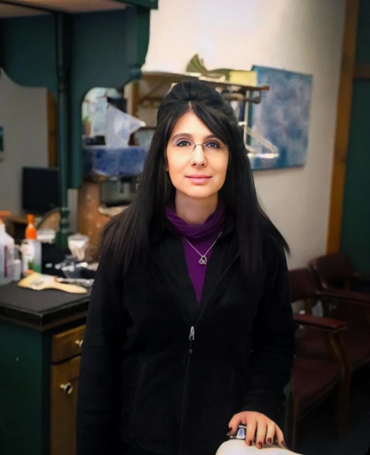 Lisa in the shop, standing behind a barber chair