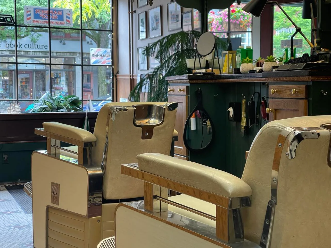 Two cream barber chairs facing the shop's front window